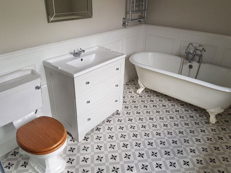 Bathroom with a freestanding roll-top bath and patterned floor tiles