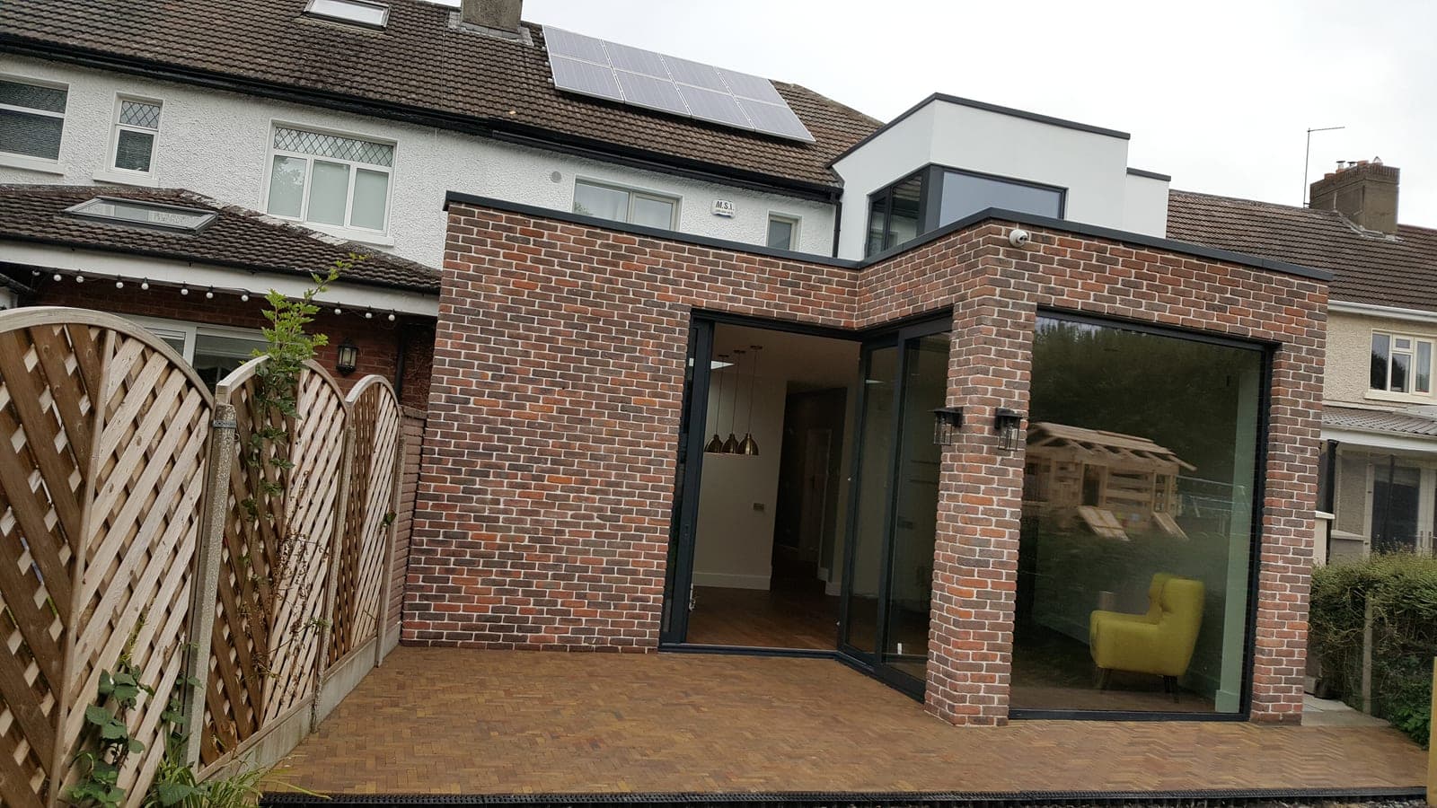 Brick extension with corner glazing beneath a rendered upper storey