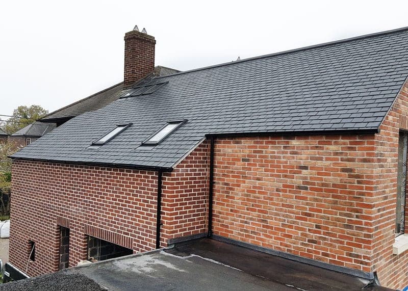 Completed brick new build with a slate roof and rooflights
